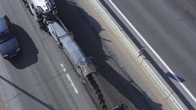 沥青碾磨将沥青表面从道路上磨碎，然后装入卡车，鸟瞰图视频素材