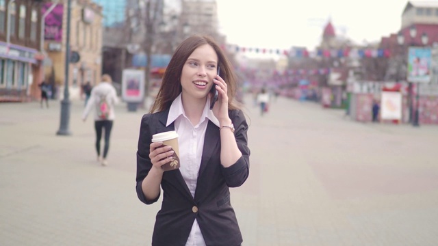 迷人的黑发商务女性在城市中使用智能手机。年轻漂亮的商业女性打电话和喝咖啡视频素材