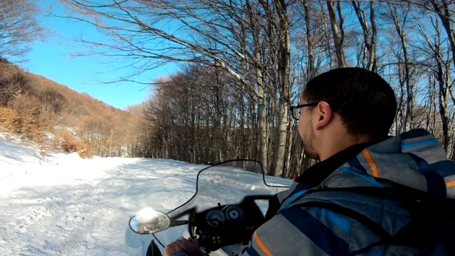 在一个阳光明媚的日子里，一名男子在森林里驾驶雪地摩托运动视频素材