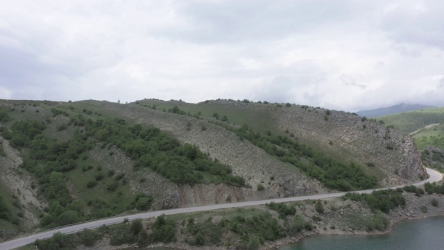 在山和湖之间的公路的鸟瞰图视频素材