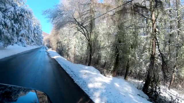 在冬天开着一辆车在下雪的路上，美丽的冬天风景和蔚蓝的天空视频素材