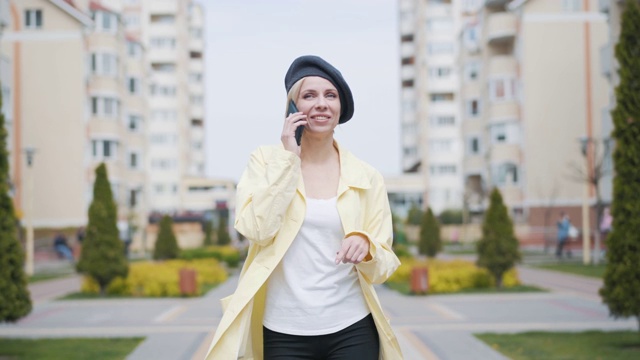 快乐积极的女人走在住宅区的巷子里，讲着电话。优雅的成年白人女士的肖像聊天和享受户外散步。快乐,生活方式。视频素材