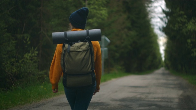 近距离的女人背双肩包走在秋天的森林自然景观旅行天气树户外树林慢动作。视频素材