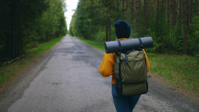 近距离的女人背双肩包走在秋天的森林自然景观旅行天气树户外树林慢动作。视频素材