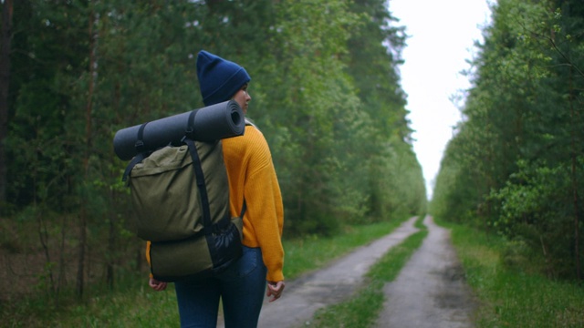 近距离的女人背双肩包走在秋天的森林自然景观旅行天气树户外树林慢动作。视频素材