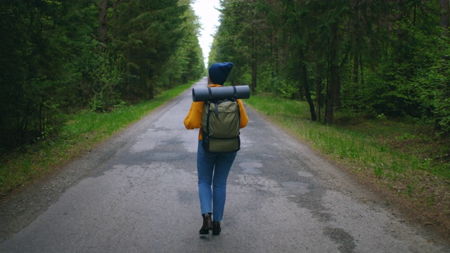 近距离的女人背双肩包走在秋天的森林自然景观旅行天气树户外树林慢动作。视频素材