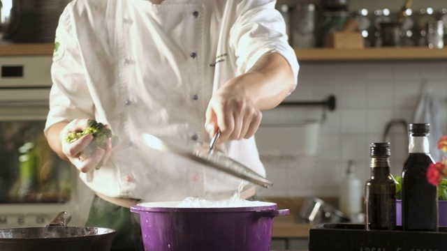 酋长打开开水壶盖。把西兰花丢进肉汤里煮。视频素材