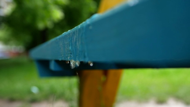 雨水从公园的长凳上流下来。春天的雨天。视频素材