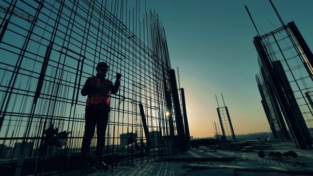 男性建筑工人编织的金属胴体在日落的背景。视频素材