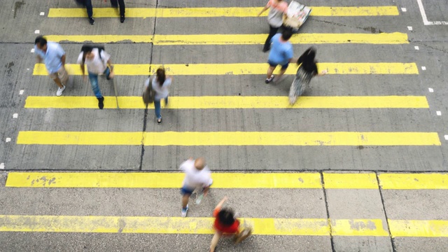 在香港孟角区，一群无法辨认的行人和汽车在黄色斑马线上行走视频素材