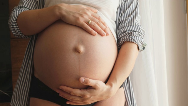 怀孕的女人感觉快乐期待母亲抱着婴儿在怀孕的肚子视频素材