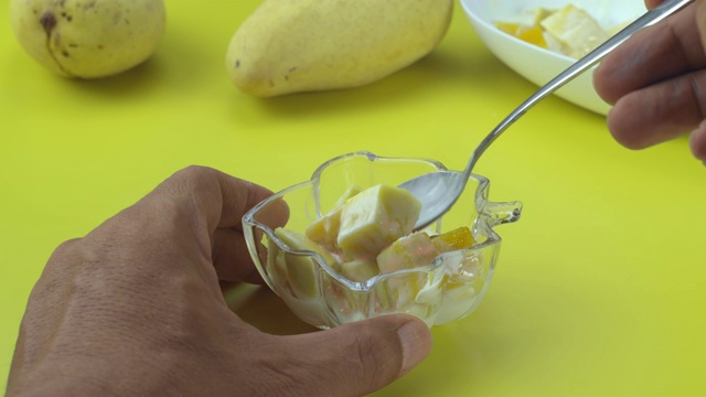 芒果倒在黄色的桌子上的酸奶里视频素材