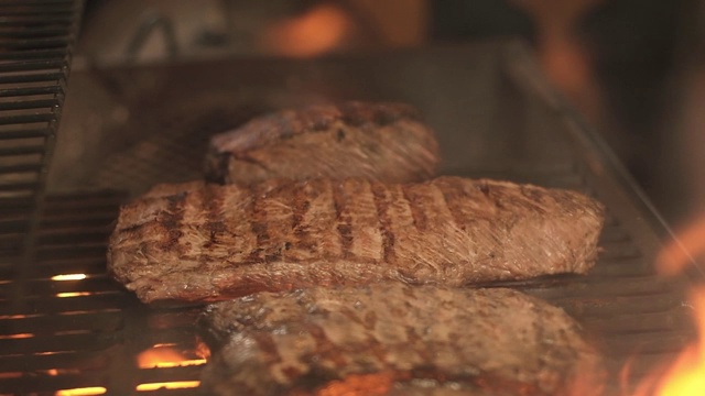 烤肉架上的肉。多汁的肉片与美丽的条纹在热烤架上与火花。烧烤。在烤架上烤的猪肉或牛肉。在屋外烧烤。视频素材