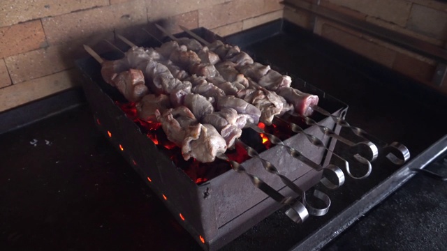 特写烟熏肉烧烤户外烧烤。火盆上烤肉串上冒着烟。烧烤派对用木炭熏烧烤。视频素材