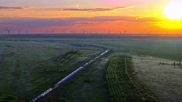 火车，草地上的铁路，远处的风车，夕阳的天空，鸟瞰图视频下载