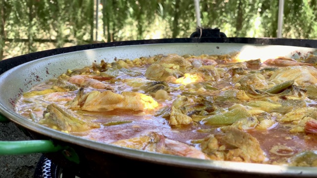 一个肉菜饭沸腾。户外烹饪来自西班牙瓦伦西亚的传统美食，米饭，鸡肉，兔肉，蔬菜和对虾视频素材