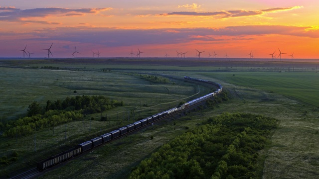 火车，草地上的铁路，远处的风车，夕阳的天空，鸟瞰图视频下载