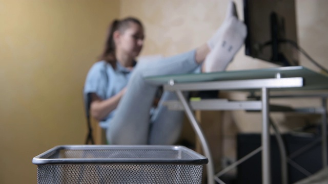 女孩威严地坐在桌边，把皱巴巴的纸片扔进垃圾桶视频素材