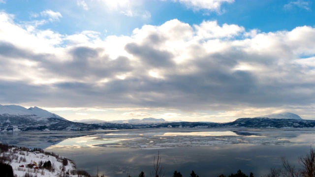 美丽的挪威风景，白雪覆盖的山脉，冬季湖泊和乌云天空与漂浮的暴风雨的云反射在水中视频素材