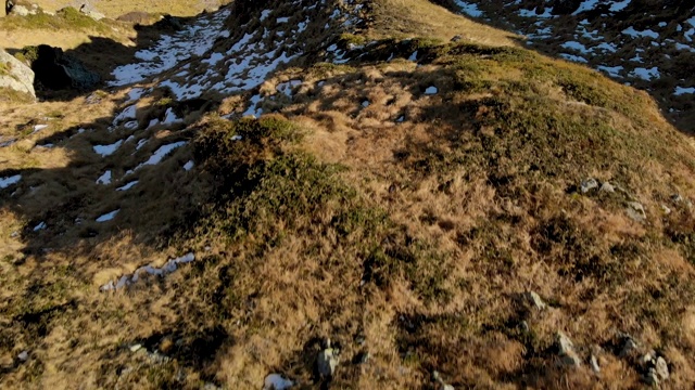 无人机飞过在陡峭的山脊上穿着黄色夹克背着背包的徒步旅行者视频素材