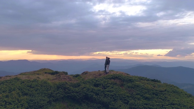 一个男人和一个女人站在一座山上，背景是夕阳视频素材