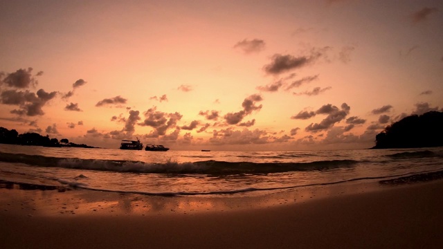 时间流逝的运动，海浪击中海滩和船背景云移动快，金色的光日出在早晨的天空视频素材