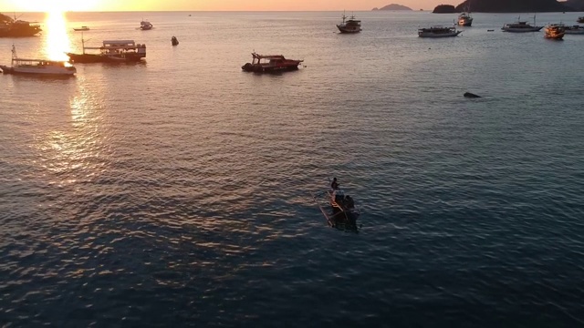 日落时分，无人机拍摄的海滩和港口。船只和码头，平静的海洋和岛屿，纳闽巴霍印度尼西亚视频素材