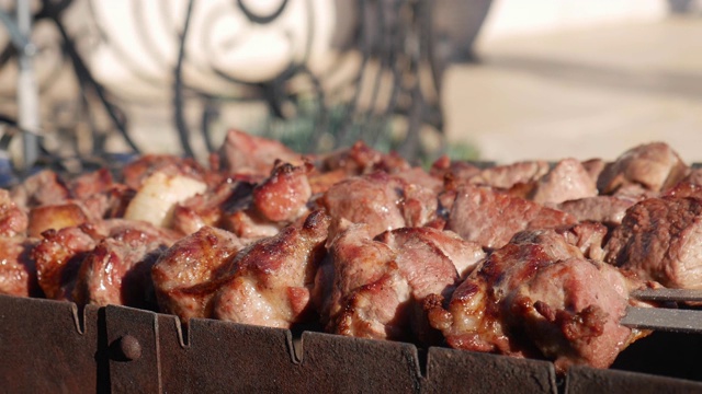 用串烤肉，把烤好的肉放在烤架上。春天的花园里，烤架上的猪肉。在大自然中烹饪烤肉串。烤肉串在炭火上煮视频素材