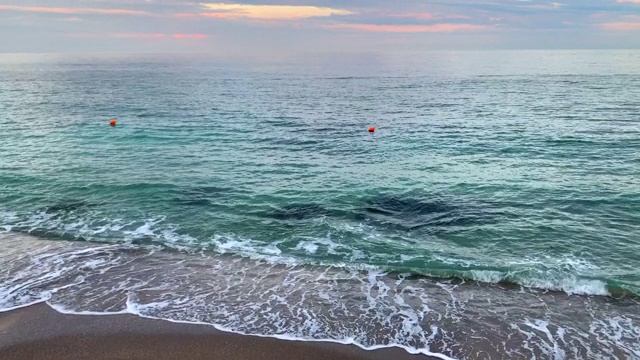 彩色的绿色海水背景与橙色浮标区在美丽的日落天空云彩。视频素材