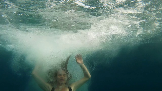 年轻女子漂浮在清澈的海水中。视频素材