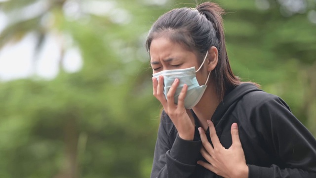 一名亚洲妇女戴口罩被限制在家时咳嗽和胸痛视频素材