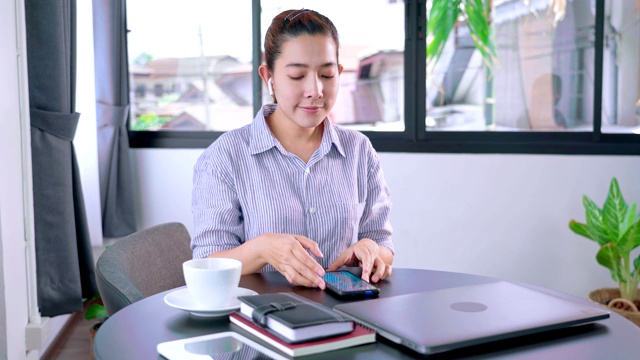 快乐微笑的年轻亚洲女子听音乐耳机和使用智能手机视频素材