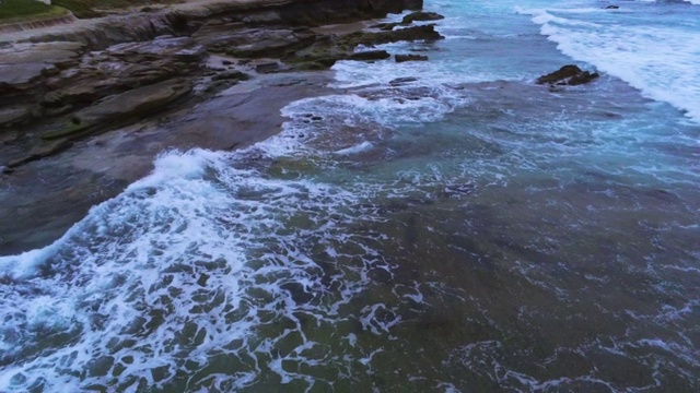 在太平洋的赤潮中，海浪拍打着岩石视频素材