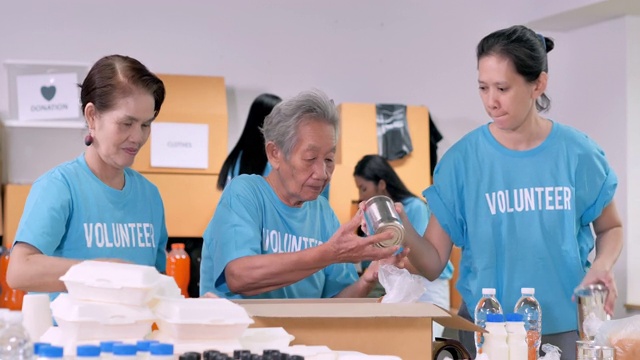 70岁的亚洲祖母，志愿者准备免费送餐，而群友打包衣服捐赠给来自冠状病毒新冠病毒危机的人。志愿服务视频素材