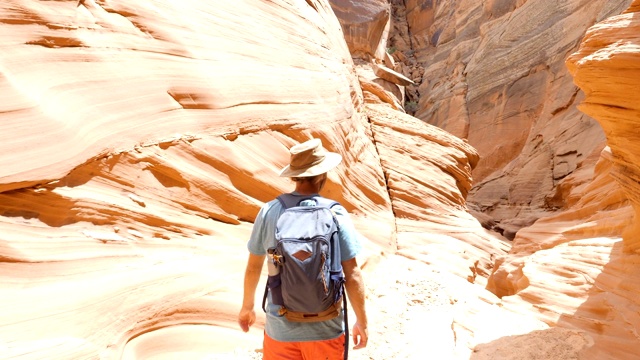 追踪羚羊峡谷里的枪手。一个年轻人在狭窄的峡谷里徒步旅行，行走在亚利桑那州的沙漠中视频素材