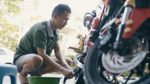 近距离男子在家里用爱心清洗摩托车或自行车，保护自己免受COVID-19冠状病毒感染。视频素材