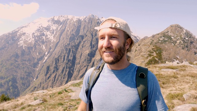 一个年轻人在山顶边徒步旅行边喝手提式水袋里的水。人们在春天进行户外活动，享受大自然视频素材