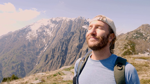 一个年轻人在山顶边徒步旅行边喝手提式水袋里的水。人们在春天进行户外活动，享受大自然视频素材