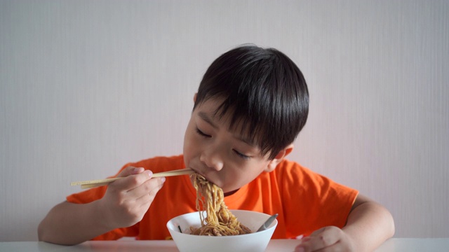 男孩在吃黄色的面条。视频素材