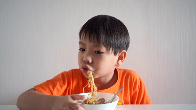 男孩在吃黄色的面条。视频素材