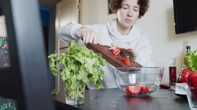 女人正坐在桌旁为自己做新鲜蔬菜沙拉视频素材