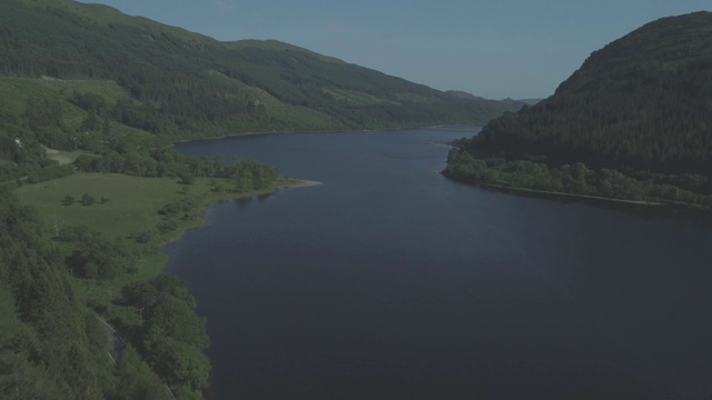 航拍接近蓝色的鲁班奈湖在Trossachs，苏格兰常绿森林上空视频素材