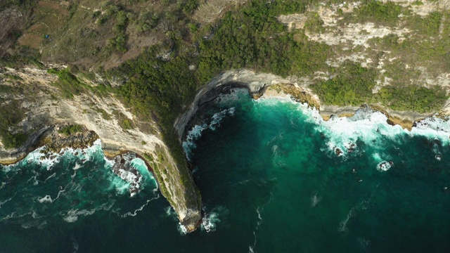 从上面俯瞰，令人惊叹的鸟瞰图，岩石嶙峋的海岸线沐浴在汹涌的大海中。努沙佩尼达，巴厘岛，印度尼西亚。视频素材