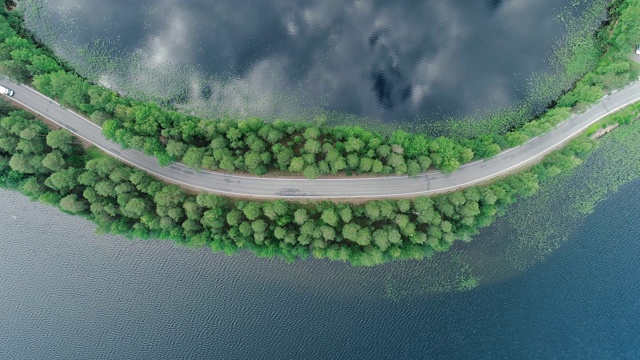 芬兰Punkaharju，汽车在一条被水包围的狭窄道路上行驶视频素材