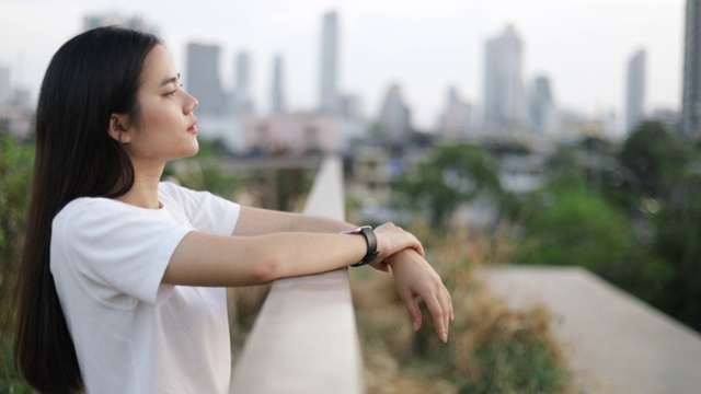 美丽的亚洲女人的肖像享受和平的日落感觉快乐放松，而站在城市的绿色地带。视频素材