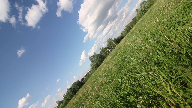 长满绿草的草地。蓝天和白云。夏季风景明媚，天气晴朗。相机在水平轴上旋转。视频素材