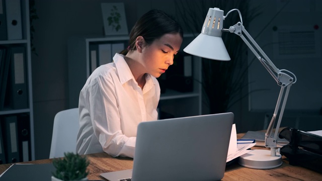 女商人晚上在办公室用笔记本电脑写笔记视频素材