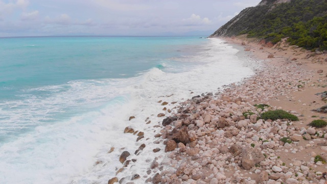 在阴天观看海岸悬崖和波涛汹涌的海洋。无人机拍摄的岩石悬崖和海浪与绿松石水，阴天视频素材