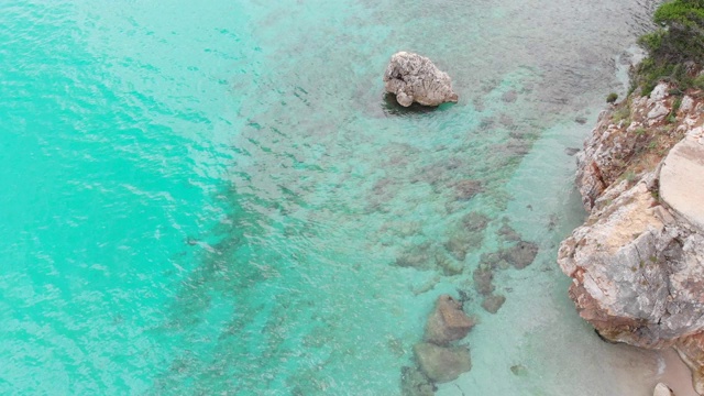 绿松石海和落基海岸。美丽的野生海滩与绿松石绿色透明的水和岩石海岸，从上面直接观看视频素材