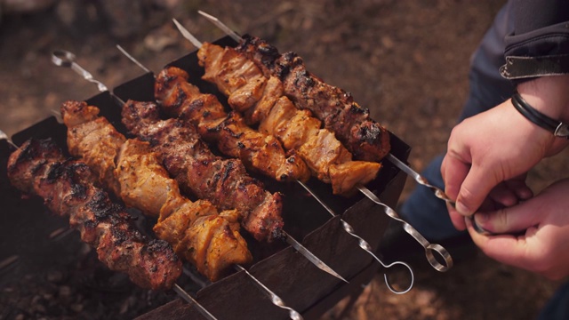 男手在户外烧烤肉。野餐时用木炭烧烤肉。视频下载